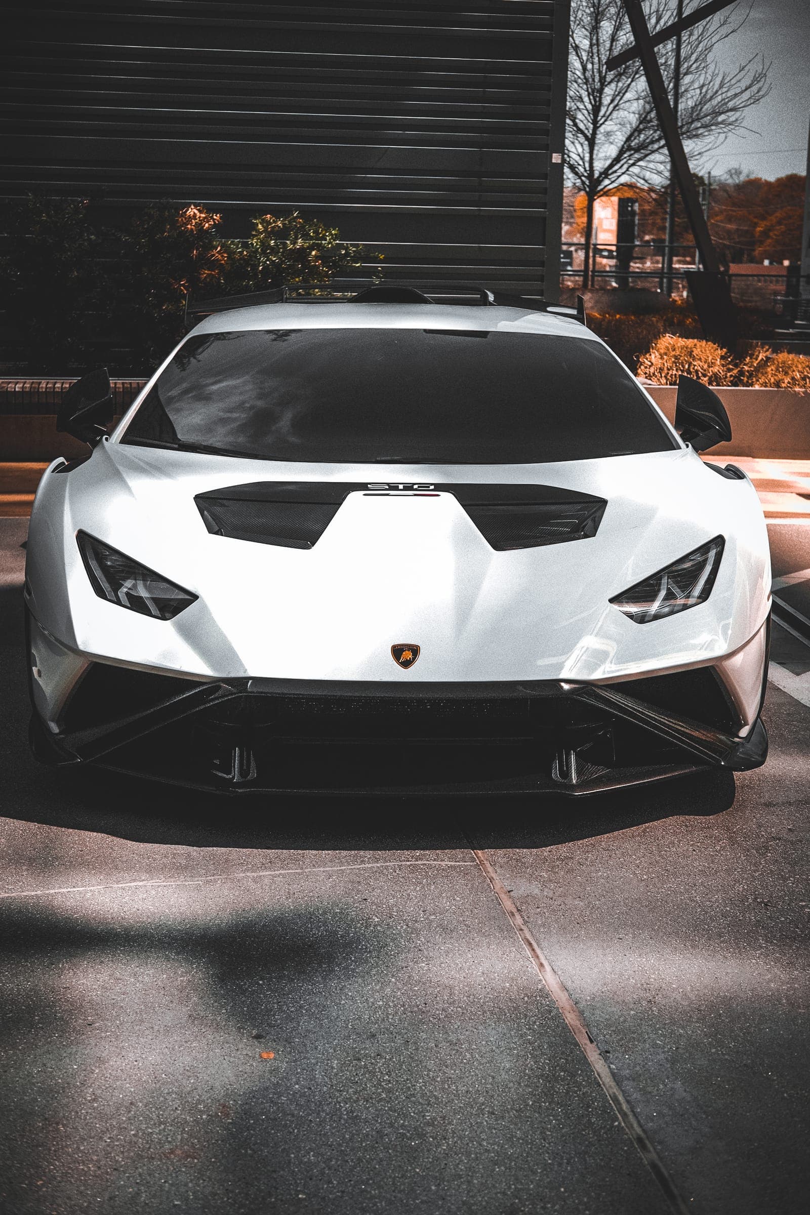 Lamborghini Huracán STO straight-on against dark slatted side-lot shadow.